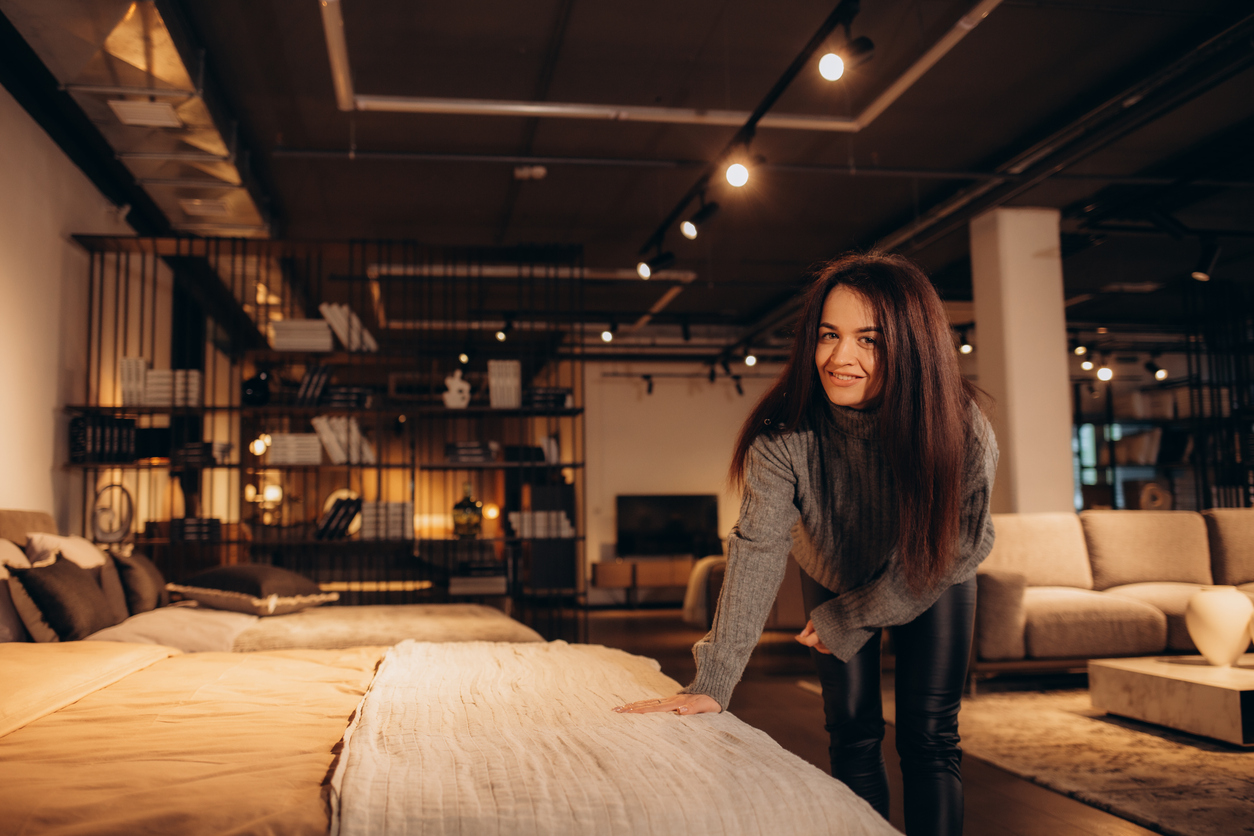 iStock Credit: Fenton Roman A smiling woman testing a mattress in a store
